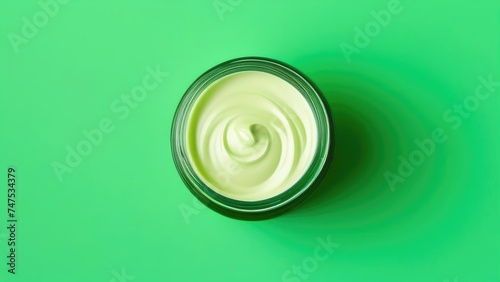 Jar of cosmetic cream on solid green background, top view. Space for text, empty space.