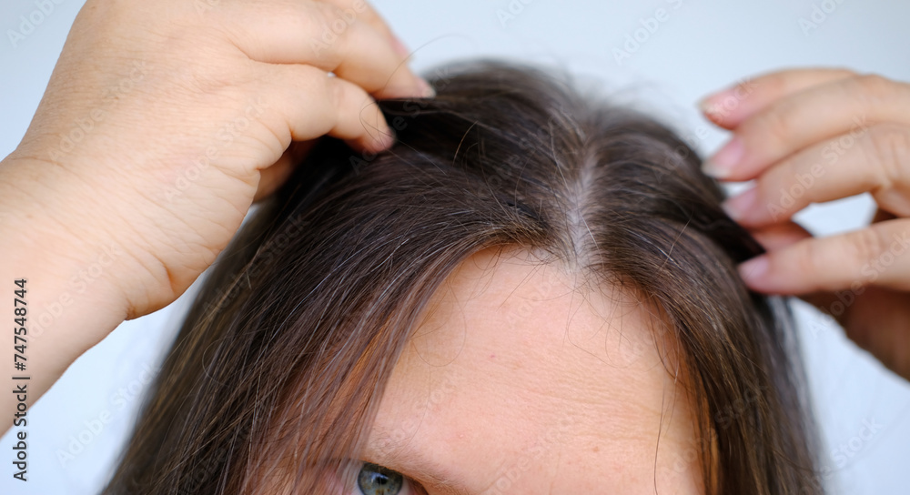 close up middle-aged female face, woman 45-50 years old looks gray hair, carefully examines hair, Aging with grace and confidence, age-related changes, Self-esteem and self-image at any age close up middle-aged female face, woman 45-50 years old looks gray hair, carefully examines hair, Aging with grace and confidence, age-related changes, Self-esteem and self-image at any age