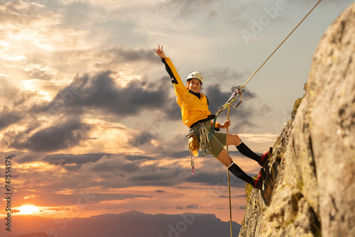 woman climbing in the mountain at sunset with lus rays, security, confidence business woman, rope access, life insurance. photo
