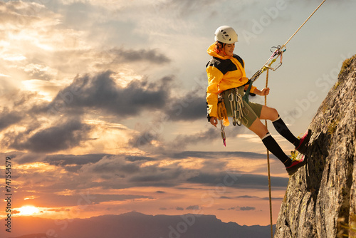 woman climbing in the mountain at sunset with lus rays, security, confidence business woman, rope access, life insurance. photo
