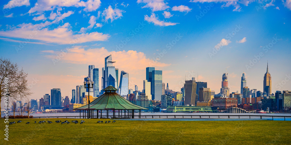 Hoboken Pier C Panoramic Viewpoint Park at Sunrise with Brant Geese grazing on the green lawn and New York City Lower Manhattan Skyline and skyscrapers in the background in New Jersey, USA