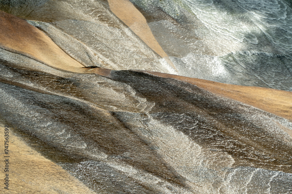 Water cascading over rocks, creating intricate textures and patterns in a mesmerizing display of nature's artistry.