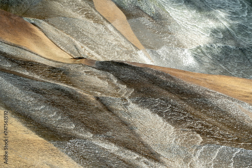 Obraz na płótnie Water cascading over rocks, creating intricate textures and patterns in a mesmerizing display of nature's artistry. w salonie