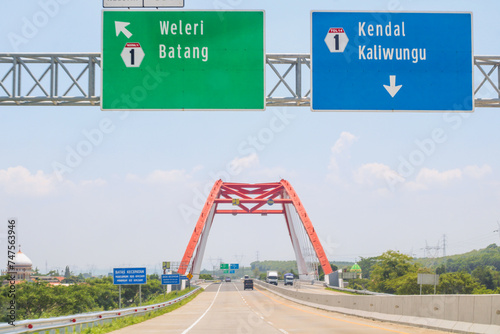 Trans Java Toll Road with signs bearing the names of destination cities Weleri and Batang on the left, destination cities Kendal and Kaliwungu remain straight photo