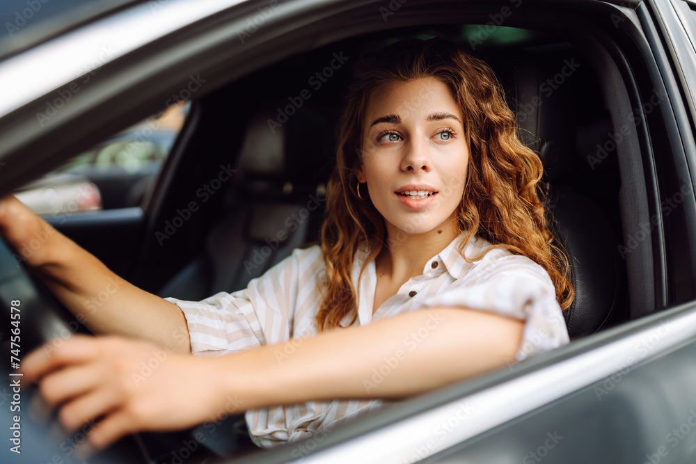 Female driver. Portrait of young beautiful woman in  sweater sitting in the car. Car travel, tourism, carshering concept.