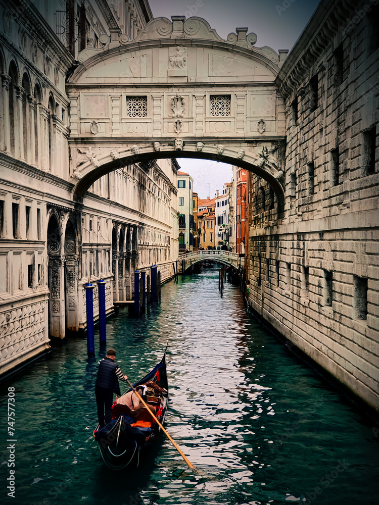 A gondolier is navigating his gondola in Venice, Italy, showcasing historic architecture and canal