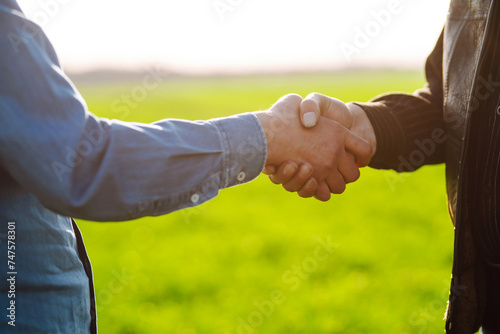 Farmer's handshake against the backdrop of a green wheat field. Successful deal. Agriculture and business concept.
