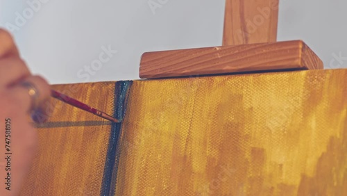 Camera panoramic move following the brush. Artist makes a brush stroke painting a picture. Warm colors painting in the art workshop.  