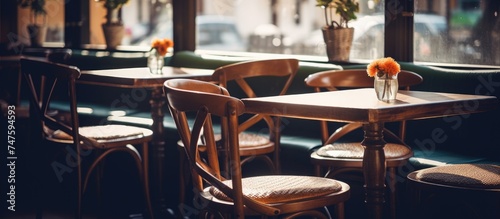 A couple of wooden tables are placed side by side in a vintage restaurant interior. The tables are empty and feature simple chair decorations, creating a cozy and inviting atmosphere.