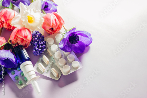 Seasonal spring allergy. Antihistamine pills and nasal spray flat lay with purple pink flowers. Healthcare for allergic. photo