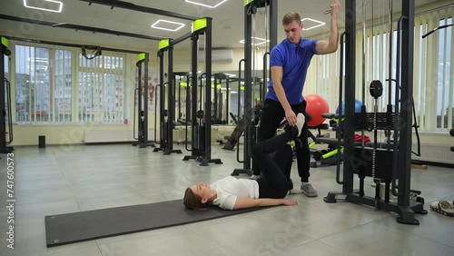 A man and woman working out in a gym, exercising their legs on gym flooring. photo
