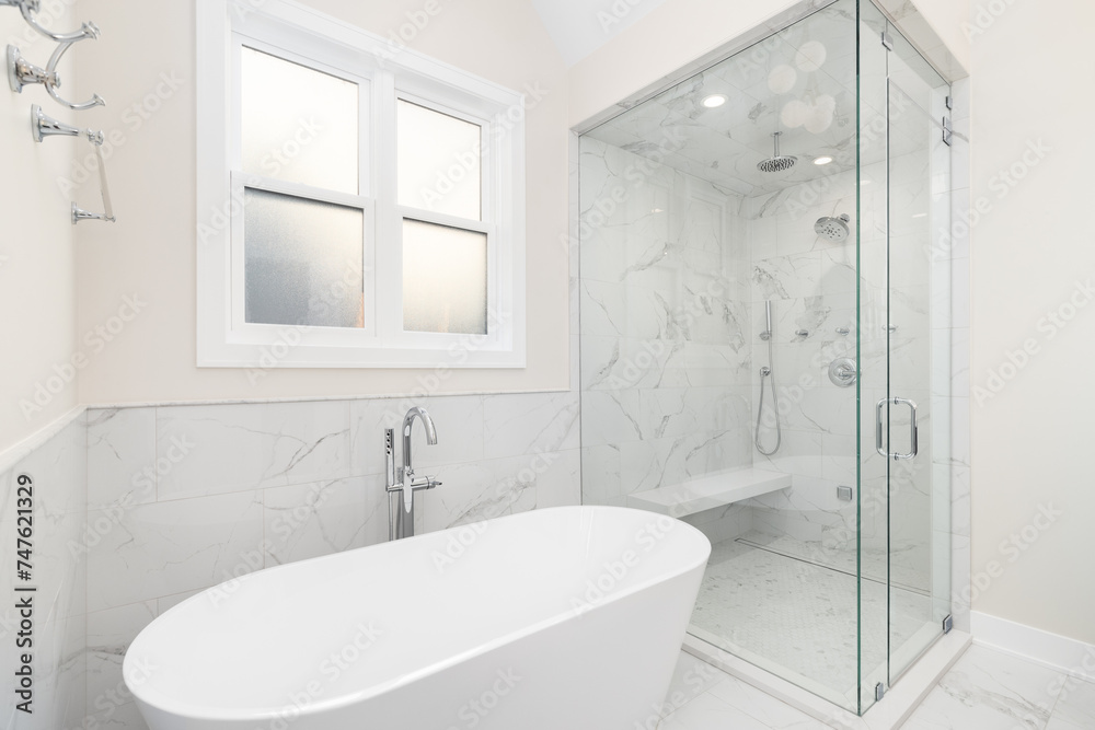 A bathroom's freestanding tub with a chrome faucet, marble tile on the walls and floor, and a walk-in shower with marble walls and bench. No brands or labels. A bathroom's freestanding tub with a chrome faucet, marble tile on the walls and floor, and a walk-in shower with marble walls and bench. No brands or labels.
