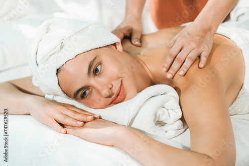 Beautiful caucasian woman having back massage by Thai professional masseur. Attractive woman feel deep in relaxation surrounded by aroma and essential oil. Relaxing and calm concept. Tranquility.