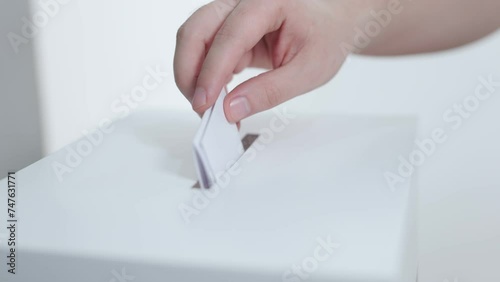 close up of a hand of a person putting his vote in a ballot box. Democratic elections day