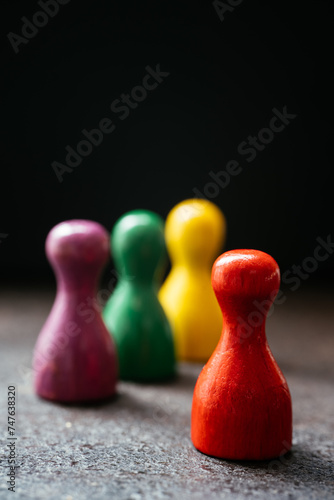 Three pawn-style playing pieces standing together and a red one in a distance from them
