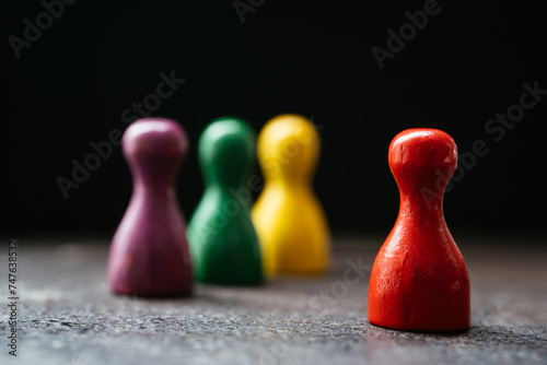 Three pawn-style playing pieces standing together and a red one in a distance from them