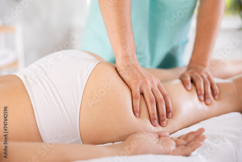 Anti-cellulite thigh massage in the salon close-up. Masseur doing leg massage to woman