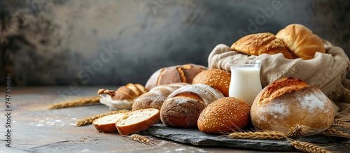 A stone table is adorned with an assortment of crusty bread rolls and a glass of milk, creating a visually appealing arrangement.