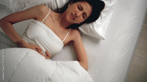 Beautiful asian woman have insomnia because of her period pain and cramp problem nightmare. She cannot sleep and stomach ache or menstruation. Young woman having period pain sleep troubles trying. photo