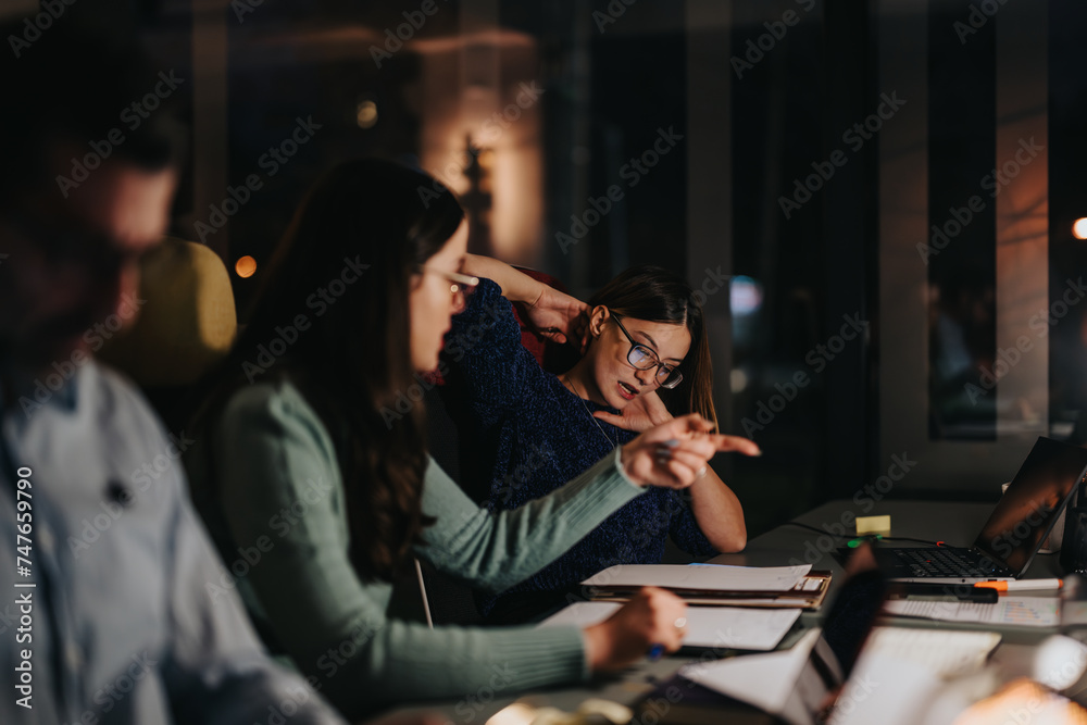 Focused multigenerational business colleagues engaged in a late-night meeting at the office, brainstorming and strategizing.