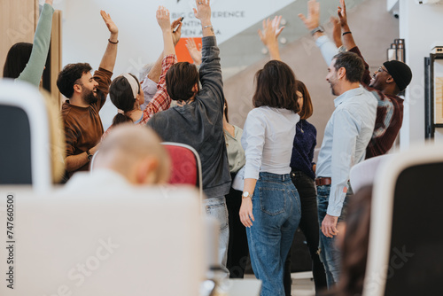A joyful team in an office setting raises their hands high in a gesture of victory and team spirit, embodying collaboration and motivation. photo