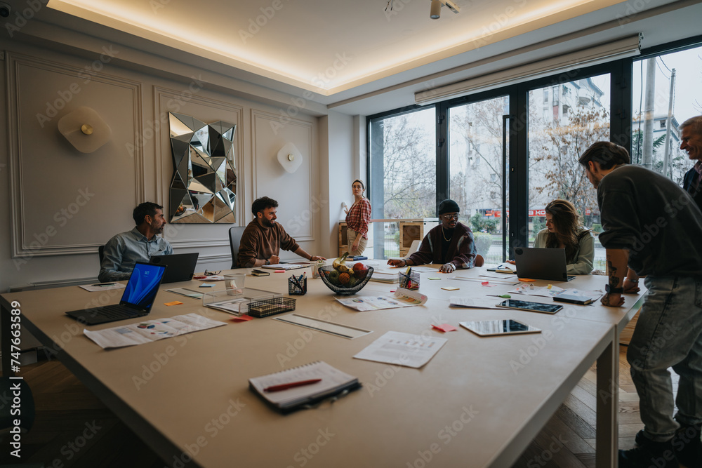 A multiethnic team engages in a business meeting in a well-lit, contemporary office. The image captures teamwork, discussion, and planning. A multiethnic team engages in a business meeting in a well-lit, contemporary office. The image captures teamwork, discussion, and planning.