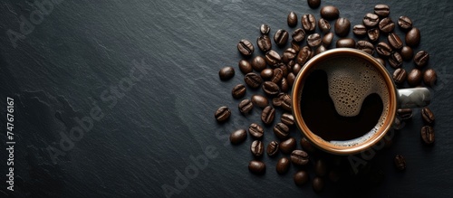 A bold and beautiful cup of black coffee is placed on a rustic black background, creating a captivating blend of elegance as it is surrounded by coffee beans. photo