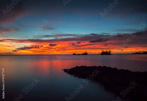 An ocean view of the sunset from Agat  Guam with a breakwater in the foreground