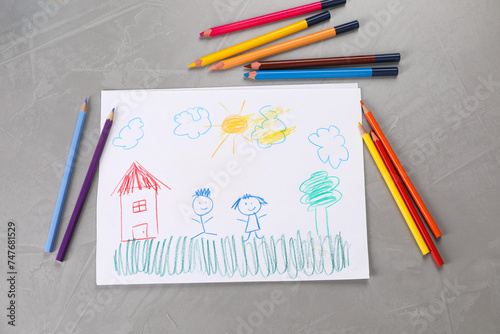 Cute child`s drawing and colorful pencils on grey textured table, flat lay photo