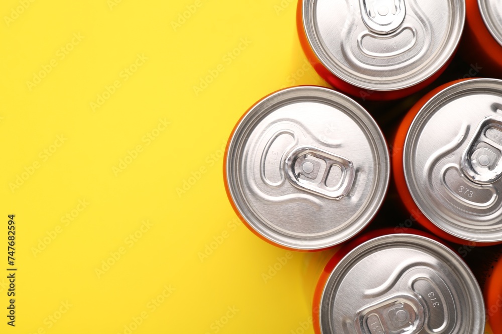 Energy drink in cans on yellow background, top view. Space for text Energy drink in cans on yellow background, top view. Space for text