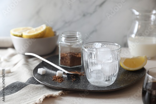 Cooking iced coffee. Ice cubes in glass, ingredients and spoon on white wooden table, closeup