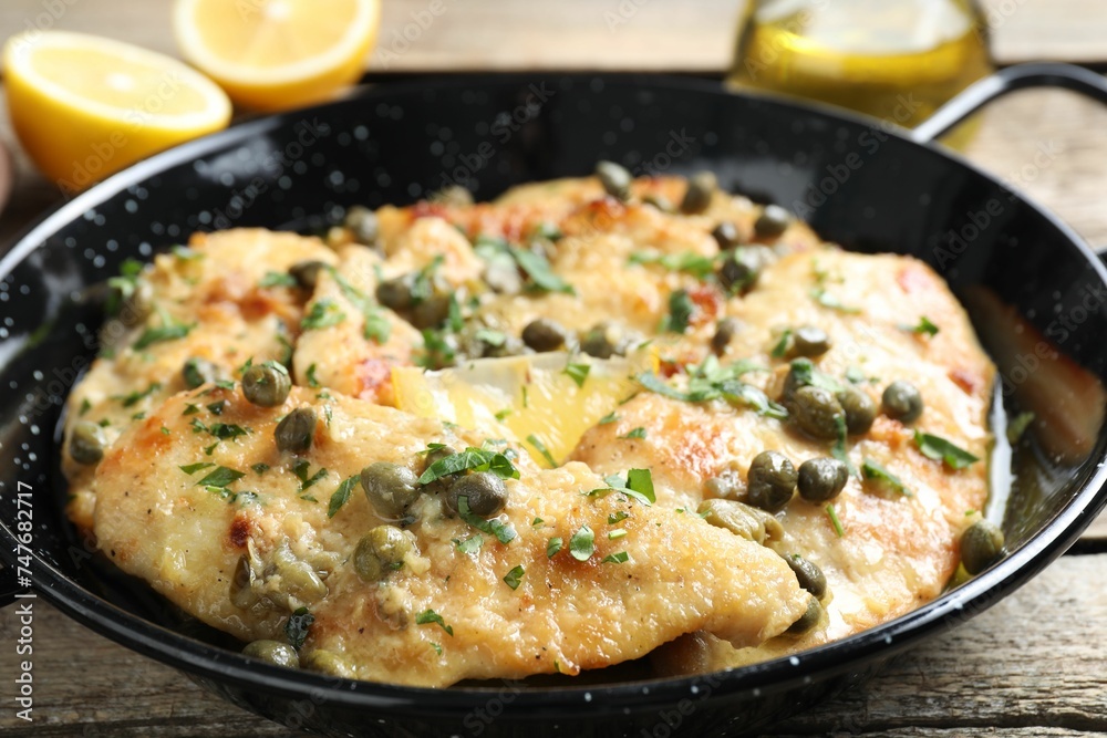 Delicious chicken piccata with herbs on wooden table, closeup Delicious chicken piccata with herbs on wooden table, closeup