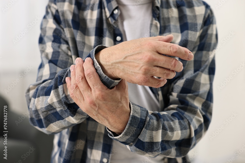 Arthritis symptoms. Man suffering from pain in wrist at home, closeup