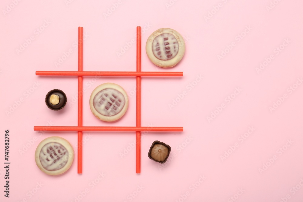 Tic tac toe game made with cookies and sweets on pink background, top view. Space for text Tic tac toe game made with cookies and sweets on pink background, top view. Space for text