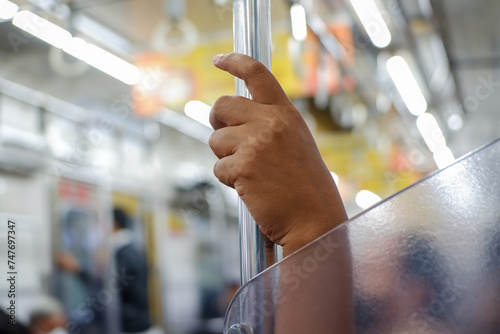 Person Hands holding a pole inside a commuterline train