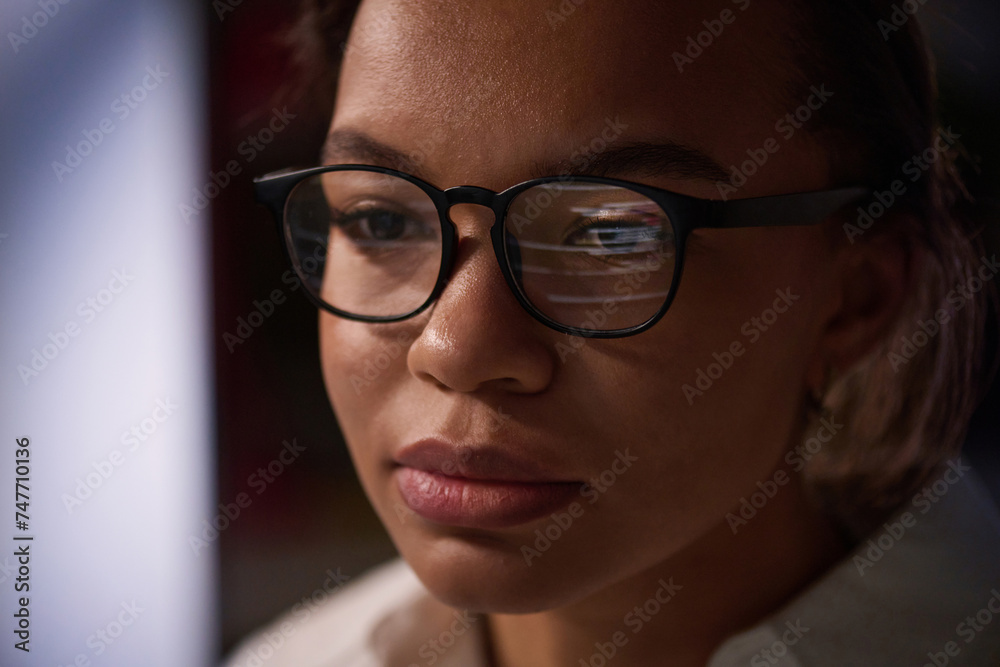 Closeup shot of young female programmer wearing eyeglasses working on code in IT company office late at night Closeup shot of young female programmer wearing eyeglasses working on code in IT company office late at night