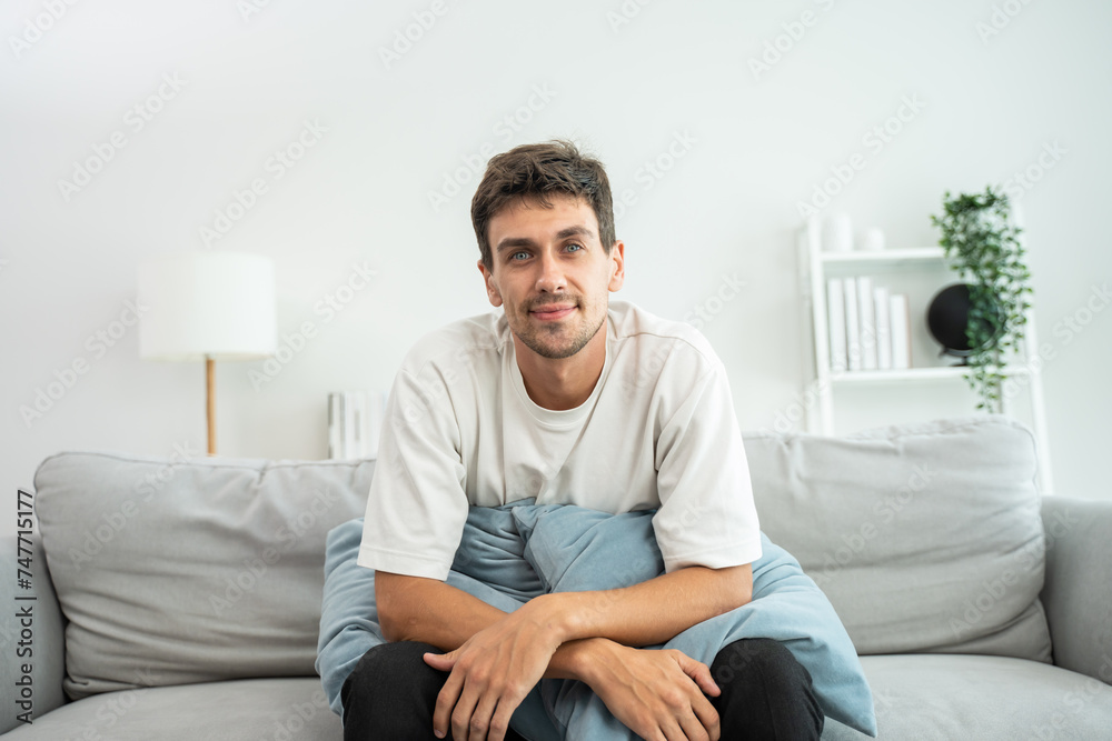 Portrait of young Caucasian man sitting on sofa in living room at home. 