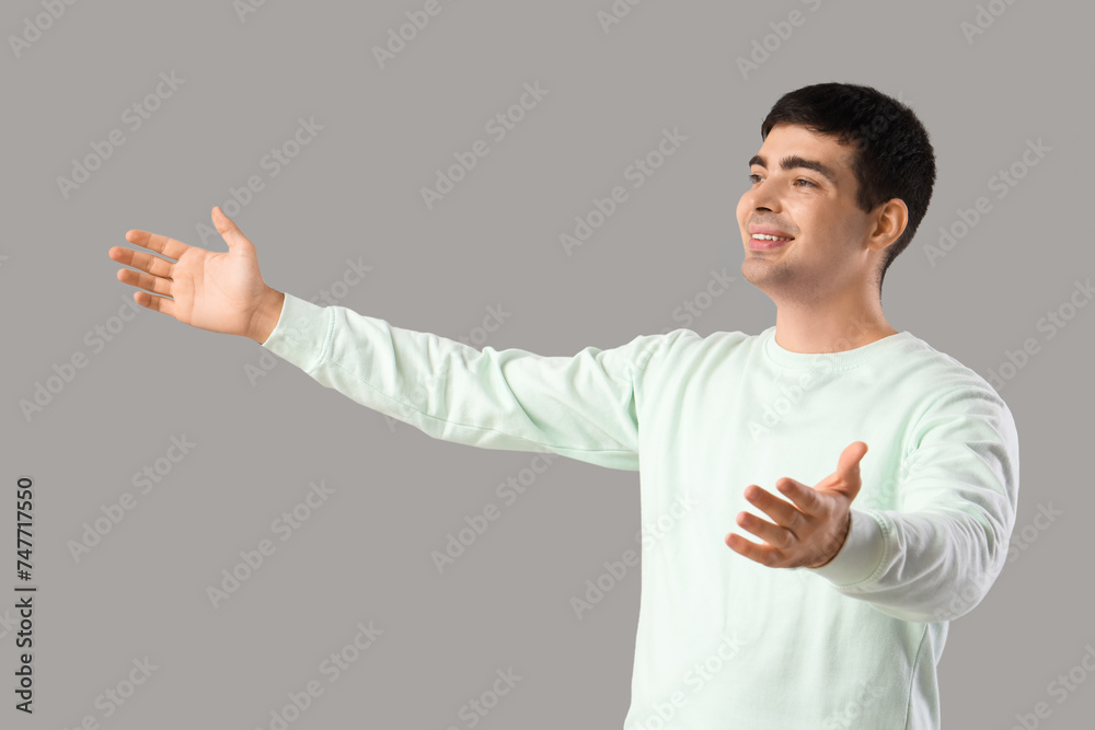 Young man opening arms for hug on light background Young man opening arms for hug on light background
