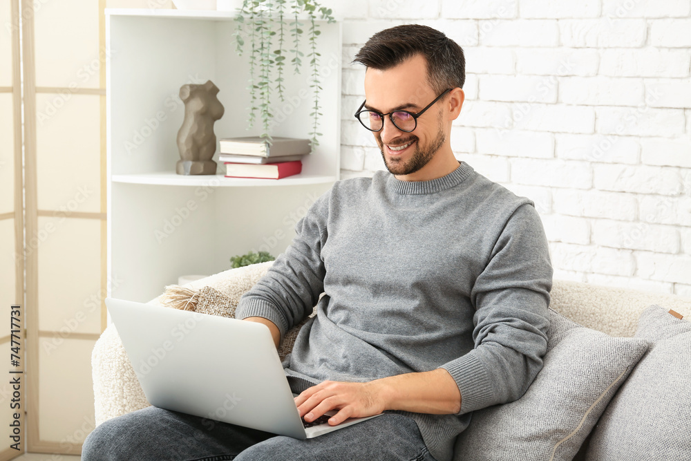 Handsome man using laptop on sofa in living room Handsome man using laptop on sofa in living room