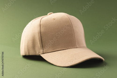 A beige baseball cap is positioned against a green background, with copy space © vectorfusionart