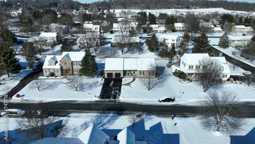 Aerial panorama shot showing snowy american village in suburb. Sunny day and melting snow on street. Forest landscape  in background. Wide shot. photo