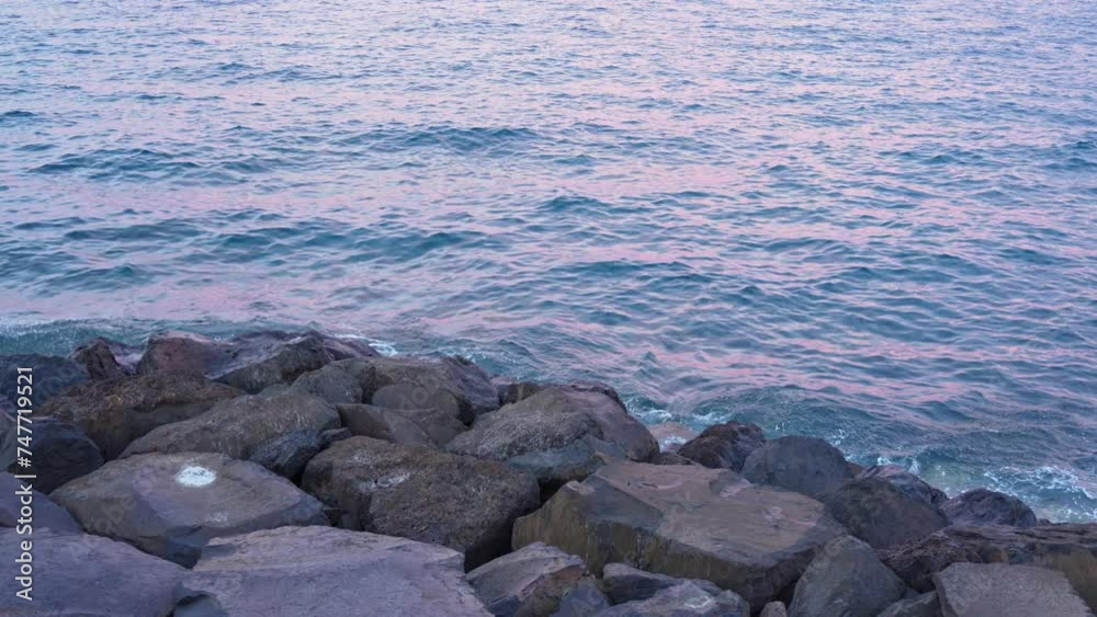 Sunset glow reflecting on ocean water near rocky coastline Sunset glow reflecting on ocean water near rocky coastline