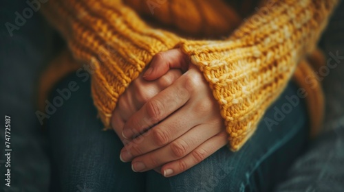 Close-up of a person's hands clasped together for warmth, wrapped in the comfort of a soft, yellow knitted sweater, warm Hands clasped in cozy knitted sweater.