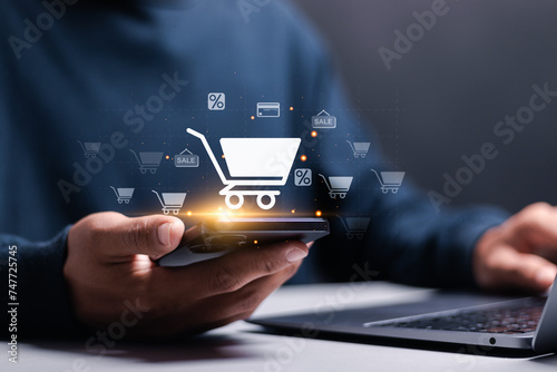 Business ecommerce concept. Person use smartphone and laptop with online shopping cart icon on virtual screen. online purchase, ecommerce store, online business, shopping on the internet. photo