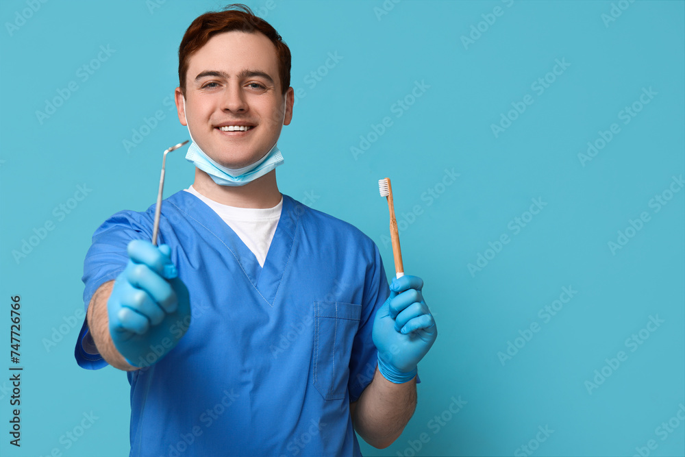 Male dentist with toothbrush and dental mirror on blue background. World Dentist Day Male dentist with toothbrush and dental mirror on blue background. World Dentist Day
