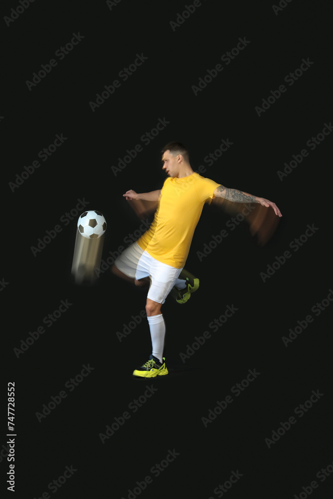 Young man playing with soccer ball in motion on black background