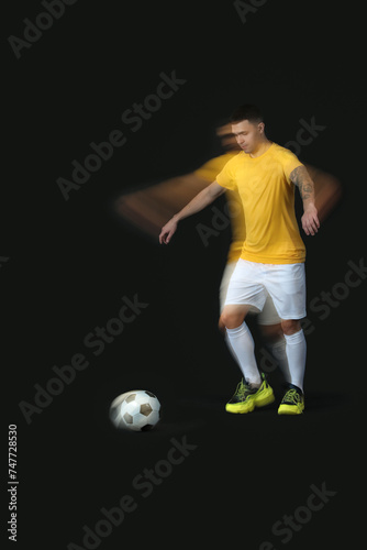 Sporty young man playing with soccer ball in motion on dark background