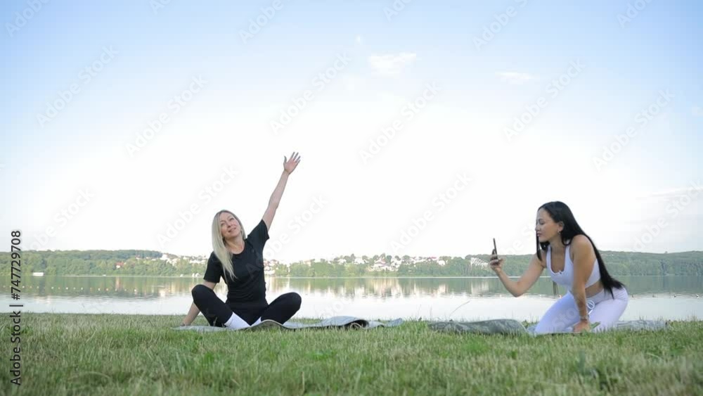 Two beautiful women practicing yoga on the bank of a beautiful pond Two beautiful women practicing yoga on the bank of a beautiful pond