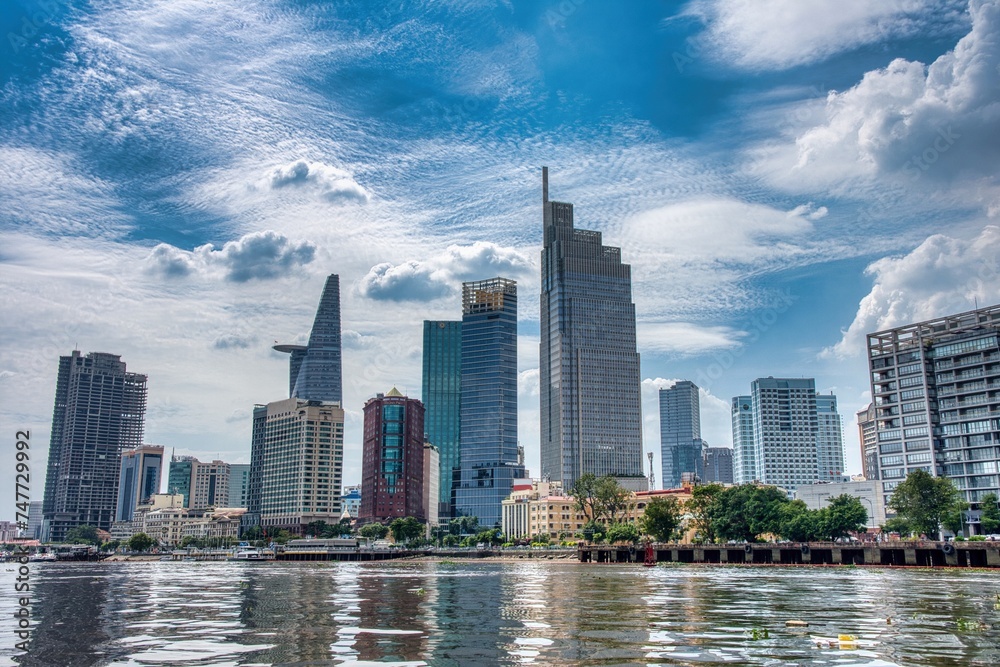 Fototapeta premium Ho Chi Minh City skyline and the Saigon River. Amazing colorful view of skyscraper and other modern buildings at downtown. Ho Chi Minh City is a popular tourist destination of Vietnam.
