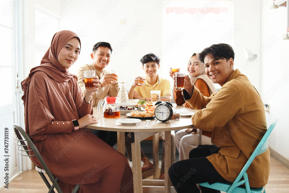 Group of young muslim people sitting on dining table and looking at camera when breakfasting together in Ramadan Group of young muslim people sitting on dining table and looking at camera when breakfasting together in Ramadan